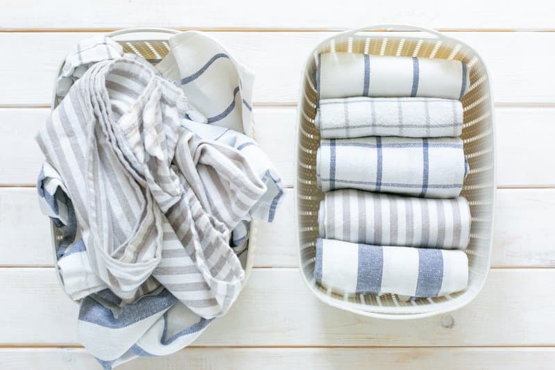 folded kitchen linens in white basket