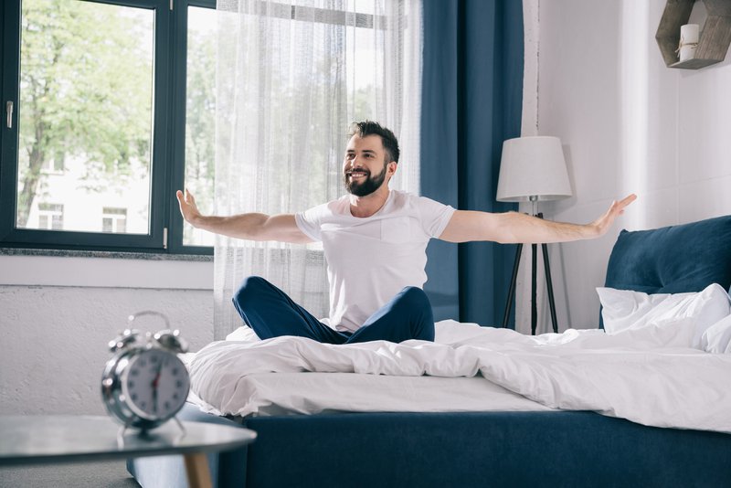 Hombre en pijama en su cama feliz