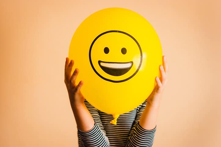 Un cliente feliz detrás de un globo sonriente