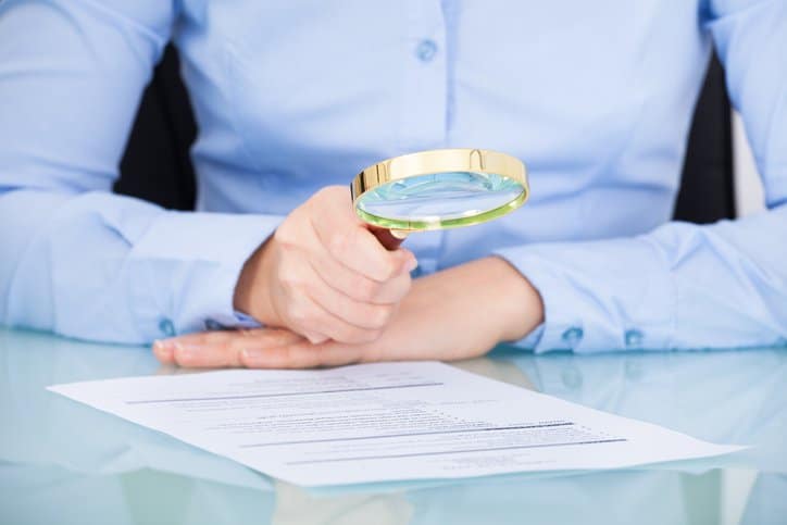 Businesswoman looking at resume with a magnifying glass