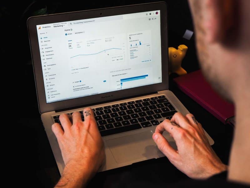 Una persona escribiendo en una computadora portátil con Google Analytics abierta mostrando KPI de comercialización digital