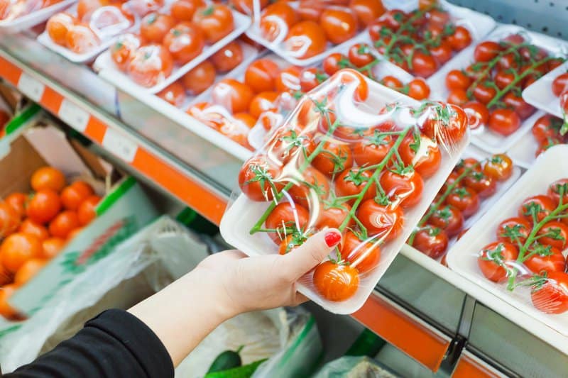 Packaged tomatoes in a woman's hand.
