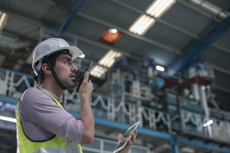Side profile of a technical engineer talking on walkie talkie in the factory