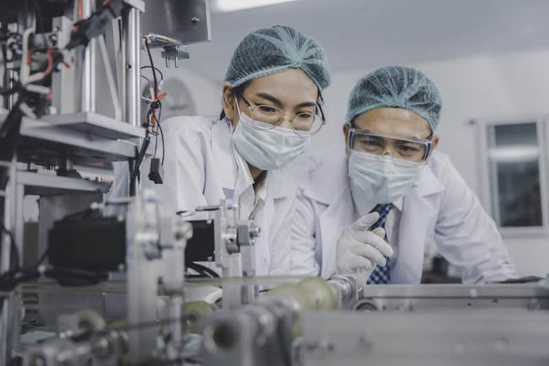 Two Asian doctor or engineer working at clean medical mask production factory, Production hygiene medical manufacturing qaulity inspection concept