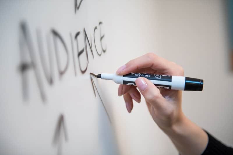A person writing audience in a white board 