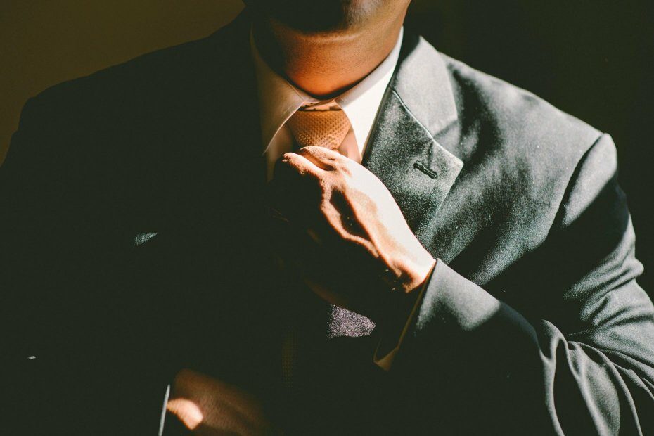 A man adjusting his tie, representing an executive presence metaphorically