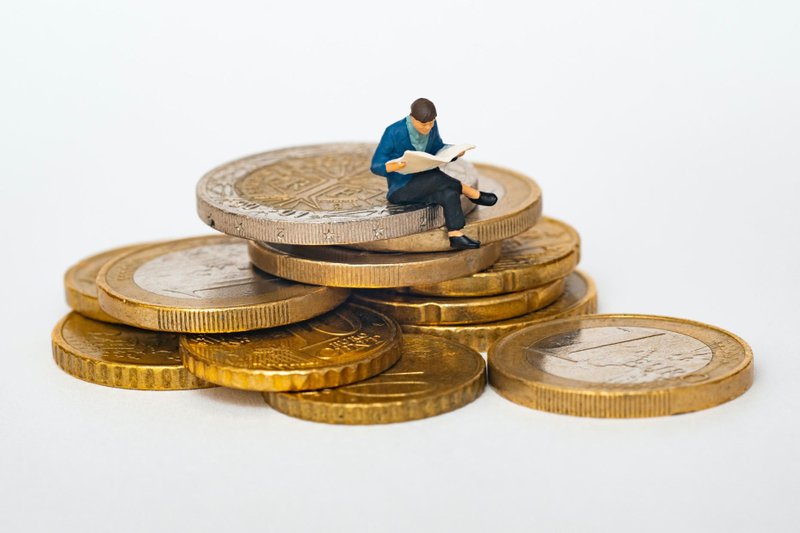 A miniature person sitting on coins